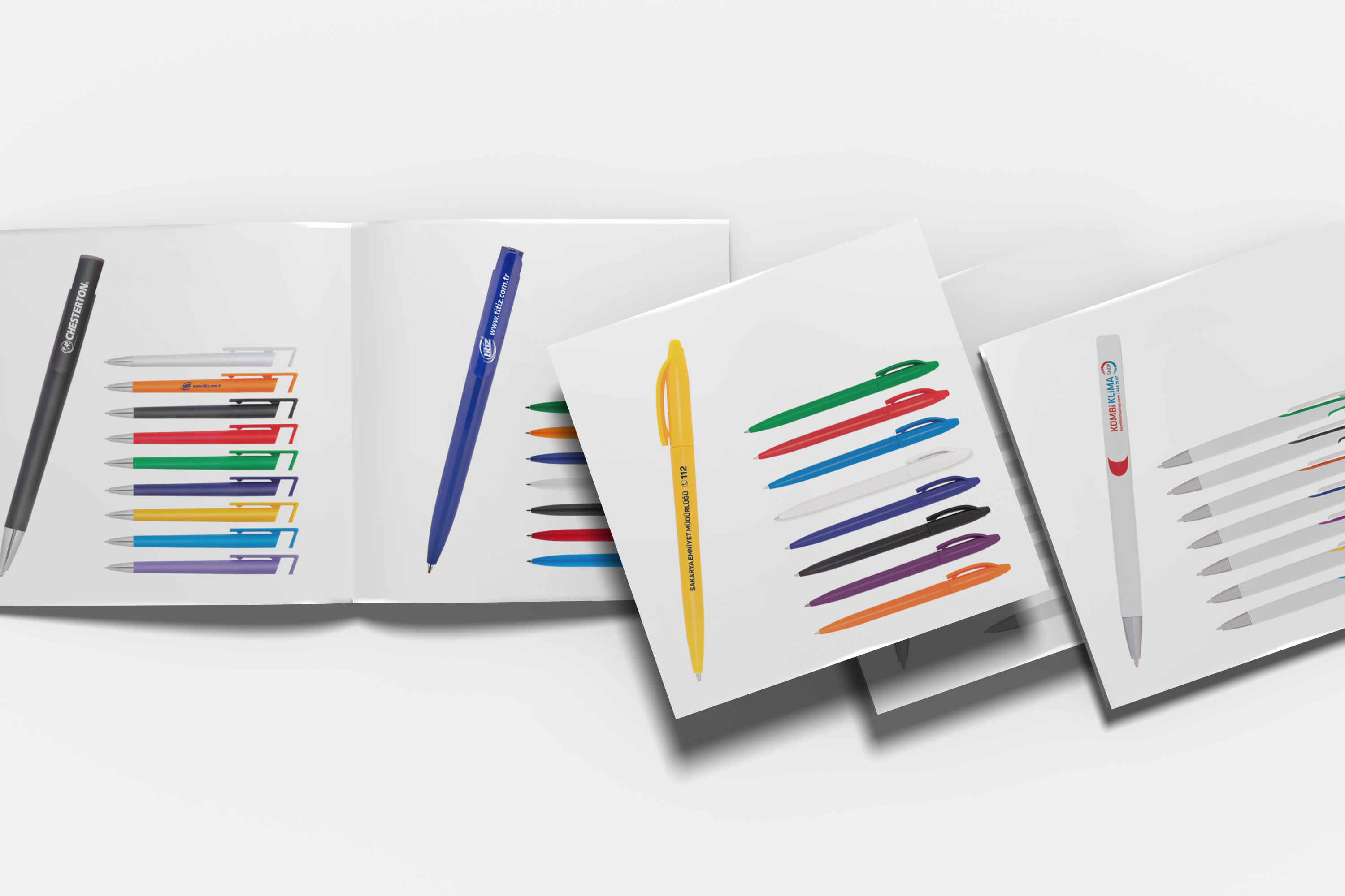 Farklı renklerde ve baskılı logolu çok sayıda tükenmez kalem broşürü, açık kitap şeklinde dizilmiş.
